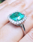 A brides' May birthstone emerald ring on a person's finger.