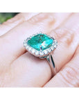 3.69 ct cushion cut Colombian emerald engagement ring with diamond halo in 18K white gold.