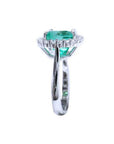 Cushion cut Colombian emerald engagement ring with diamond halo in 18K white gold.