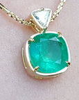 A genuine colombian emerald pendant with gold setting on a light skin background
