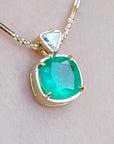 Gold necklace with a Muzo colombian emerald pendant on a light skin background