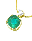 Gold necklace with a natural cushion cut emerald pendant on a white background