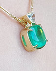 Gold pendant with a natural cushion cut colombian emerald on a light skin background