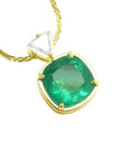Gold necklace with a natural colombian emerald pendant on a white background