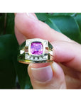 Men's 18K yellow gold ring with a bezel-set cushion-cut purplish-pink sapphire and diamond accents.