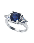 14K white gold ring with a deep blue cushion-cut sapphire and two trillion-cut white sapphires.