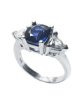 Deep blue cushion cut sapphire ring with trillion side sapphires in white gold.