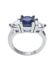 14K white gold cushion cut deep blue sapphire ring with two trillion side sapphires.