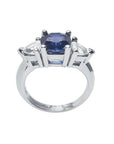 14K white gold cushion cut deep blue sapphire ring with two trillion side sapphires.