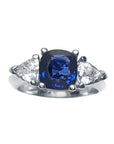 Women's cushion cut natural sapphire ring with trillion side white sapphires made of 14k white gold.