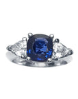 Women's cushion cut natural sapphire ring with trillion side white sapphires made of 14k white gold.