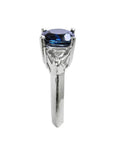 Deep blue cushion-cut sapphire ring with trillion side sapphires in white gold.