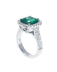 A cushion cut emerald ring in white gold, top and lateral profile visibles.