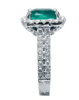 Cushion cut Colombian emerald ring with alo diamond and side accent diamonds on the band, side profile view.