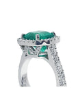 Cushion cut 3.92 ct. natural emerald ring in 14K white gold with diamond halo and pavé band.