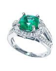 This emerald cushion cut and accent diamond ring displays the top and lateral side.