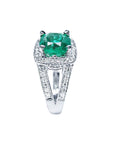 A white gold cushion cut emerald ring and diamond-studded band on a white background.