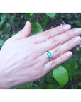 1.45 ct cushion-cut natural emerald ring with diamond halo on a hand, 14K gold band.