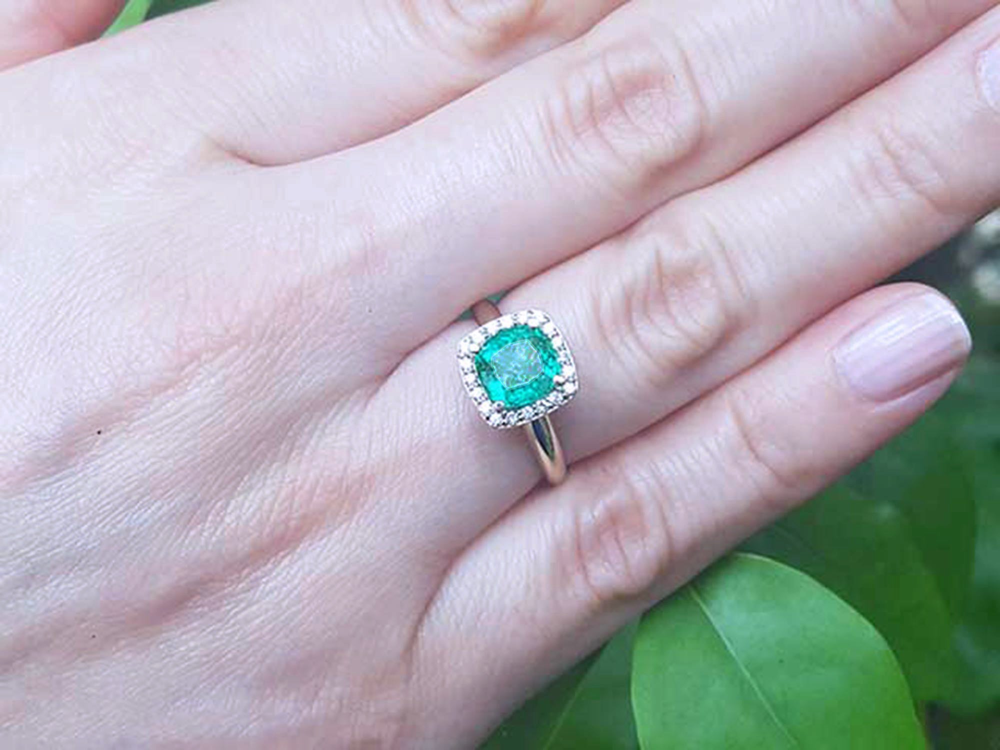 Emerald ring on a hand with a green leafy background.