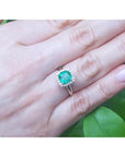 1.45 ct natural cushion-cut emerald ring with diamond halo on a woman's hand.