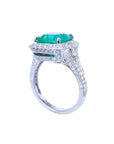 Cushion cut 3.68 ct emerald engagement ring in 18K white gold with diamond halo and pave band.