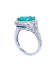 Cushion cut 3.68 ct emerald engagement ring in 18K white gold with diamond halo and pave band.