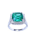 A cushion cut emerald white gold ring for women displaying a halo diamond and side profile.