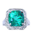 This cushion cut emerald engagement ring with a halo natural diamond in white gold is on a top side position.