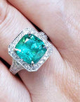 A lady's emerald ring cushion cut on a finger.