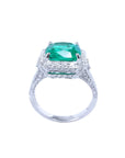 Cushion cut 3.68 ct Colombian emerald engagement ring with diamond halo in 18K white gold.