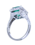 An underside profile view of a 18k gold cushion cut emerald ring for women.