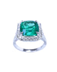 A cushion cut emerald white gold ring for women displaying a halo of natural diamond.