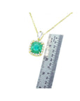 Gold necklace with a cushion natural emerald pendant next to a ruler for size reference on a white background