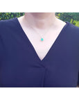 Cushion-cut emerald pendant with halo natural diamonds on a 14K yellow gold chain, worn on a model.