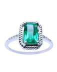 A cushion cut emerald ring in white gold displaying its topside encircled with rope like frame design.