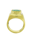 Men's gold ring with a natural emerald on a lateral position, top setting and band design displayed.