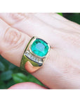 Men's 18k yellow gold ring with a cushion-cut emerald and two rows of channel-set diamonds.