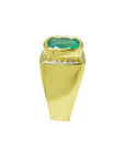 Men's 18k yellow gold ring with a cushion cut emerald and channel-set diamonds.