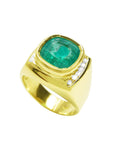 This yellow gold men's emerald ring is on a tilted position showing its top and partial lateral side.