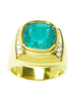 This men's gold ring with a large cushion cut natural colombian emerald is on a topside view and sideways are visibles.