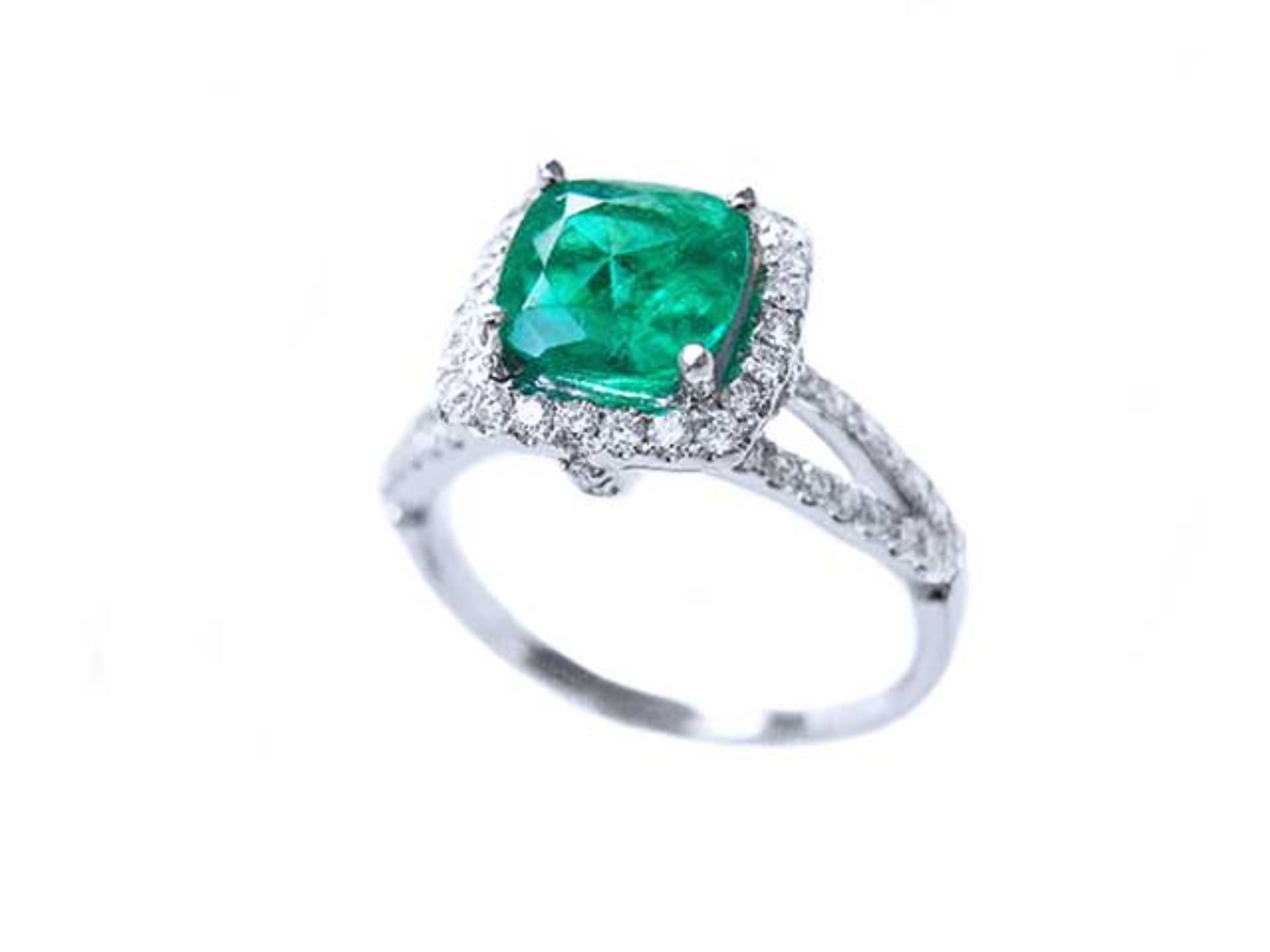 Cushion cut emerald and halo diamond ring on a white background.