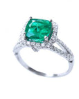 Cushion cut emerald and halo diamond ring on a white background.