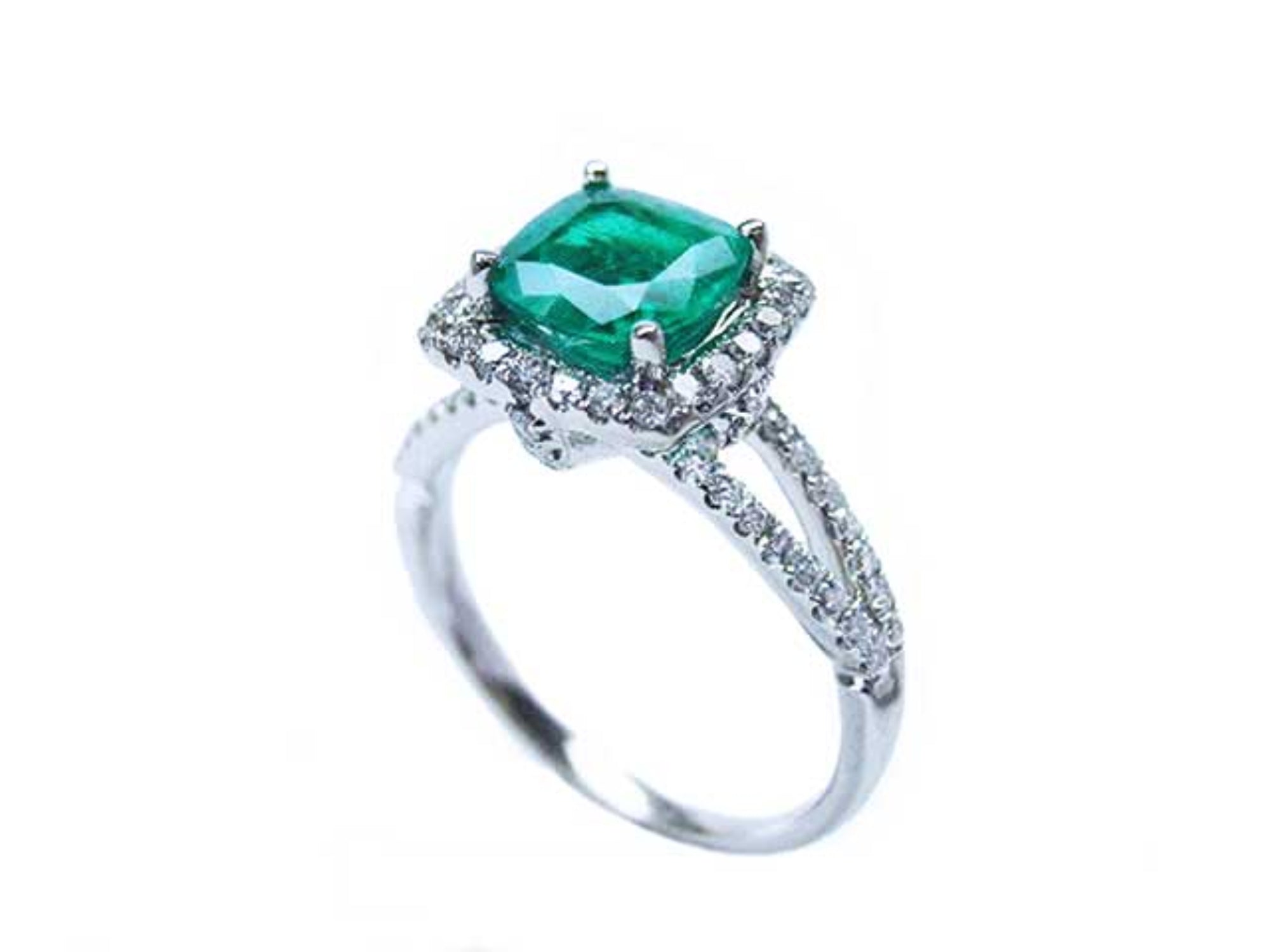 A colombian emerald cushion cut on top of the white gold ring with diamond accents, side split shank profile view.