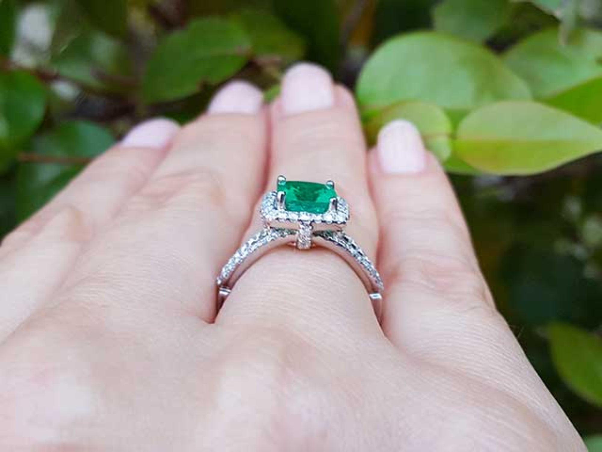 Emerald ring on a hand with a natural background.