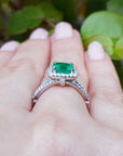 Emerald ring on a hand with a natural background.
