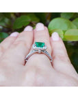 Emerald ring on a hand with a natural background.