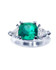 A cushion cut Muzo colombian emerald ring with trillion side natural diamonds, crafted in 1 4k white gold.
