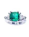 A cushion cut Muzo colombian emerald ring with trillion side natural diamonds, crafted in 1 4k white gold.