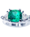 This cushion cut Emerald ring with trillion side diamonds displays the top and shoulders profile view.
