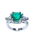 Emerald cushion cut trillion accent diamonds ring for women on a white background.